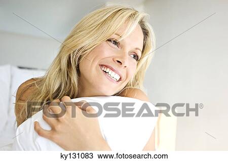 Portrait of young woman smiling, holding pillow, indoors View Large Photo Image Stock Image - Portrait of young woman smiling, holding pillow, indoors. Fotosearch
