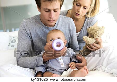 Young couple and baby sitting indoors, father feeding his son View Large Photo Image Stock Photography - Young couple and baby sitting indoors, father feeding his son. Fotosearch