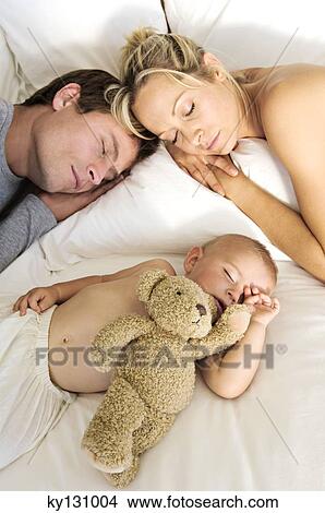 Picture - Young couple and baby sleeping, indoors. Fotosearch
