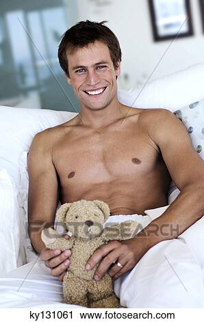 Young man smiling, looking at the camera, teddy bear in his hands, indoors View Large Photo Image Stock Image - Young man smiling, looking at the camera, teddy bear in his hands, indoors. Fotosearch