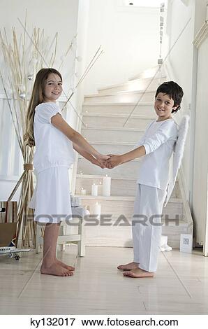 Christmas day, girl and boy posing for the camera, holding their hands each others, indoors View Large Photo Image Stock Photo - Christmas day, girl and boy posing for the camera, holding their hands each others, indoors. Fotosearch