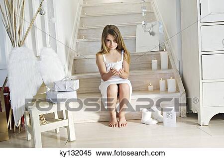 Christmas day, little girl holding a candle, sitting on stair, indoors View Large Photo Image Stock Photography - Christmas day, little girl holding a candle, sitting on stair, indoors. Fotosearch