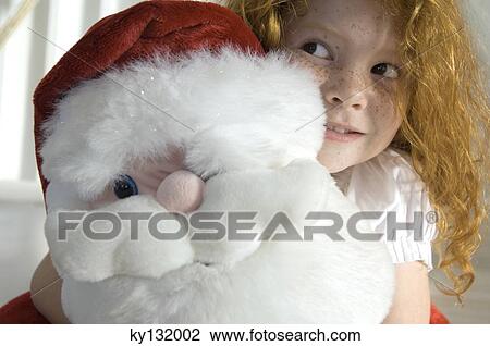 Christmas day, portrait of a little girl holding a cuddly toy (Santa Claus), indoors View Large Photo Image Stock Image - Christmas day, portrait of a little girl holding a cuddly toy (Santa Claus), indoors. Fotosearch