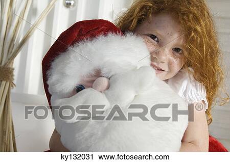 Christmas day, portrait of a little girl holding a cuddly toy (Santa Claus), indoors View Large Photo Image Stock Image - Christmas day, portrait of a little girl holding a cuddly toy (Santa Claus), indoors. Fotosearch