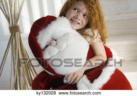 Christmas day, portrait of a little girl holding a cuddly toy (Santa Claus), indoors View Large Photo Image Stock Photo - Christmas day, portrait of a little girl holding a cuddly toy (Santa Claus), indoors. Fotosearch