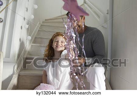 Father and daughter playing with their Christmas presents, girl holding a magic wand, indoors View Large Photo Image Picture - Father and daughter playing with their Christmas presents, girl holding a magic wand, indoors. Fotosearch