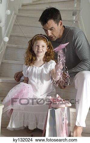 Father and daughter with Christmas presents, girl holding a princess costume, indoors View Large Photo Image Picture - Father and daughter with Christmas presents, girl holding a princess costume, indoors. Fotosearch