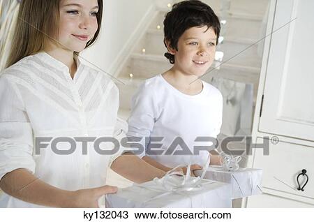Lillte girl and little boy offering Christmas presents, indoors View Large Photo Image Stock Image - Lillte girl and little boy offering Christmas presents, indoors. Fotosearch