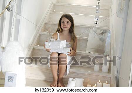 Stock Photo - Little girl holding a Christmas present, indoors. Fotosearch