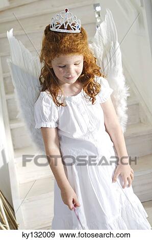 Stock Photo - Little girl in an angel costume, indoors. Fotosearch