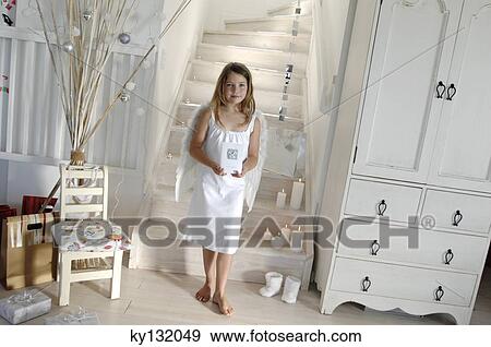 Little girl in an angel costume, holding a Christmas card, indoors View Large Photo Image Stock Photo - Little girl in an angel costume, holding a Christmas card, indoors. Fotosearch