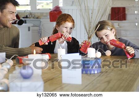 Ma ad two children sitting around table, exchanging Christmas presents, indoors View Large Photo Image Stock Photography - Ma ad two children sitting around table, exchanging Christmas presents, indoors. Fotosearch