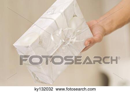 Man hand holding a present, close-up, indoors View Large Photo Image Stock Image - Man hand holding a present, close-up, indoors. Fotosearch