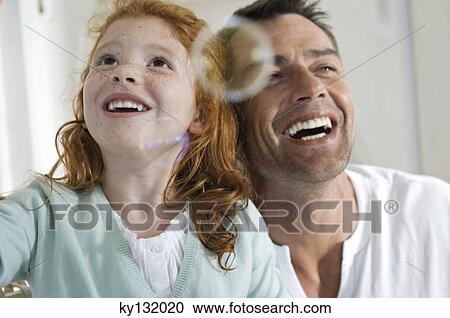 Portrait of father and daughter laughing, looking at soap bubbles, indoors View Large Photo Image Stock Image - Portrait of father and daughter laughing, looking at soap bubbles, indoors. Fotosearch