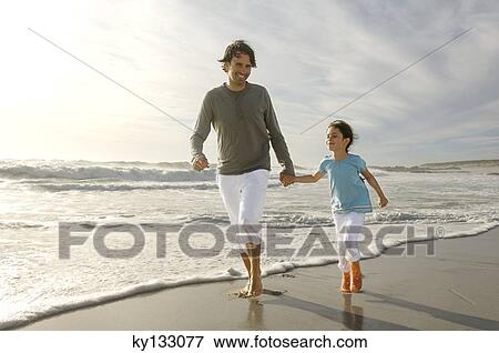 Stock Photo - Father and daughter walking on the beach, outdoors. Fotosearch