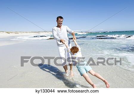 Picture - Father playing with daughter on the beach, outdoors. Fotosearch