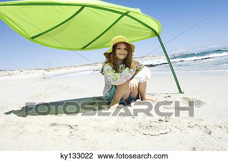 Little girl sitting on the beach under large green leaf, outdoors View Large Photo Image Stock Image - Little girl sitting on the beach under large green leaf, outdoors. Fotosearch