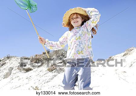 Little girl walking on the beach, holding a landing net, outdoors View Large Photo Image Picture - Little girl walking on the beach, holding a landing net, outdoors. Fotosearch