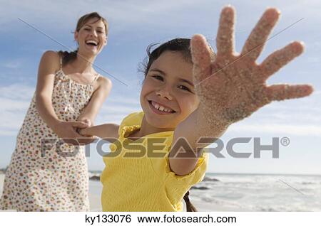 Mother and daughter on the beach, girl stretching out her hand, outdoors View Large Photo Image Stock Photograph - Mother and daughter on the beach, girl stretching out her hand, outdoors. Fotosearch