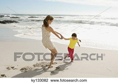 Mother and daughter playing on the beach, outdoors View Large Photo Image Stock Image - Mother and daughter playing on the beach, outdoors. Fotosearch