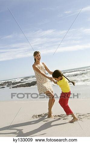 Stock Photo - Mother and daughter playing on the beach, outdoors. Fotosearch