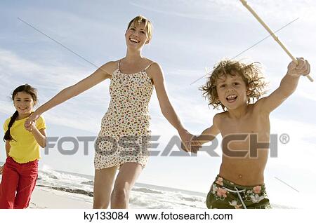 Mother and two children walking on the beach, outdoors View Large Photo Image Picture - Mother and two children walking on the beach, outdoors. Fotosearch