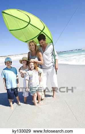 Parents and three children on the beach posing for the camera, outdoors View Large Photo Image Stock Photo - Parents and three children on the beach posing for the camera, outdoors. Fotosearch