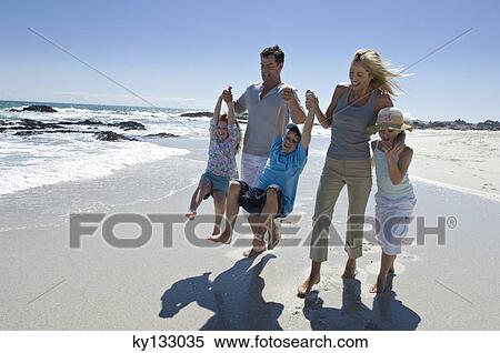 Parents and three children walking on the beach, outdoors View Large Photo Image Stock Photography - Parents and three children walking on the beach, outdoors. Fotosearch