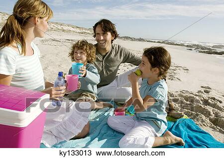 Parents and two children having a picinic on the beach, outdoors View Large Photo Image Stock Image - Parents and two children having a picinic on the beach, outdoors. Fotosearch