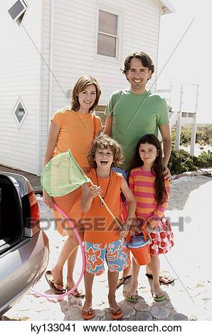 Parents and two children in front of a house, holding beach accessories, outdoors View Large Photo Image Stock Image - Parents and two children in front of a house, holding beach accessories, outdoors. Fotosearch