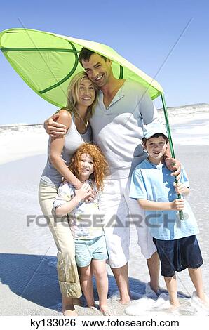 Parents and two children on the beach, posing for the camera, outdoors View Large Photo Image Stock Photograph - Parents and two children on the beach, posing for the camera, outdoors. Fotosearch