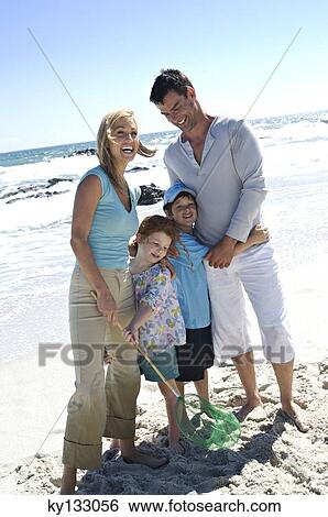Parents and two children on the beach, posing for the camera, outdoors View Large Photo Image Stock Photograph - Parents and two children on the beach, posing for the camera, outdoors. Fotosearch