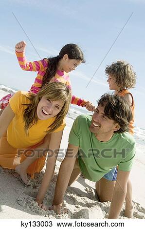 Parents and two children playing on the beach, outdoors View Large Photo Image Stock Image - Parents and two children playing on the beach, outdoors. Fotosearch