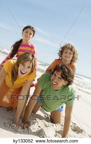 Parents and two children playing on the beach, holding daughter and son on their back, outdoors View Large Photo Image Stock Image - Parents and two children playing on the beach, holding daughter and son on their back, outdoors. Fotosearch