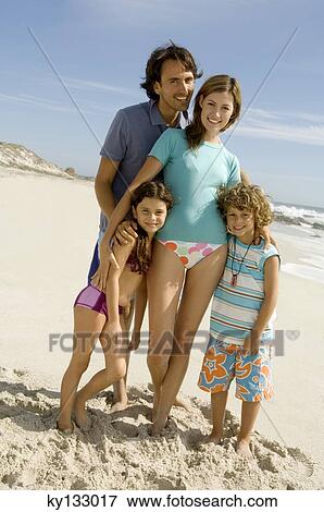 Stock Photo - Parents and two children posing on the beach, outdoors. Fotosearch
