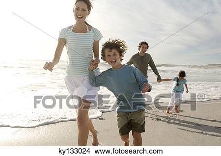 Picture - Parents and two children walking on the beach, outdoors. Fotosearch