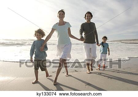 Parents and two children walking on the beach, outdoors View Large Photo Image Picture - Parents and two children walking on the beach, outdoors. Fotosearch