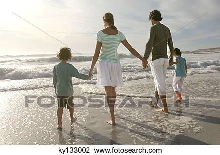 Parents and two children walking on the beach, rear view, outdoors View Large Photo Image Stock Image - Parents and two children walking on the beach, rear view, outdoors. Fotosearch