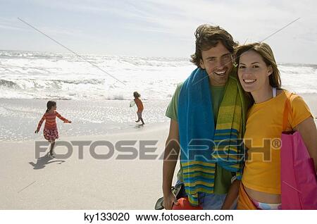 Stock Image - Parents and two children walking on the beach, outdoors. Fotosearch