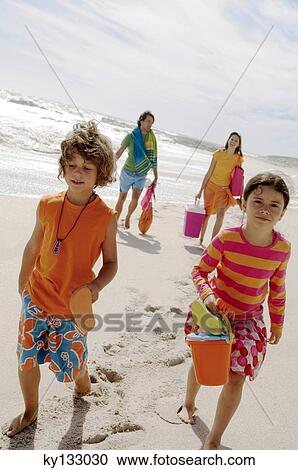 Parents and two children walking on the beach, outdoors View Large Photo Image Stock Image - Parents and two children walking on the beach, outdoors. Fotosearch