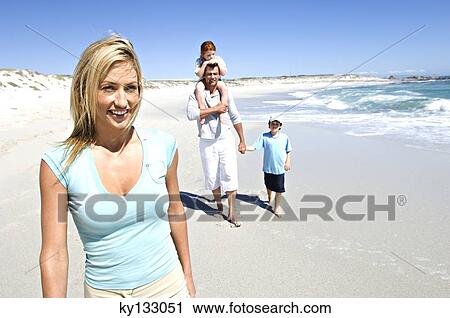 Parents and two children walking on the beach, man carrying daughter on his shoulders, outdoors View Large Photo Image Stock Image - Parents and two children walking on the beach, man carrying daughter on his shoulders, outdoors. Fotosearch