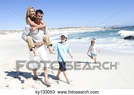 Parents and two children walking on the beach, man carrying woman on his back, outdoors View Large Photo Image Stock Image - Parents and two children walking on the beach, man carrying woman on his back, outdoors. Fotosearch