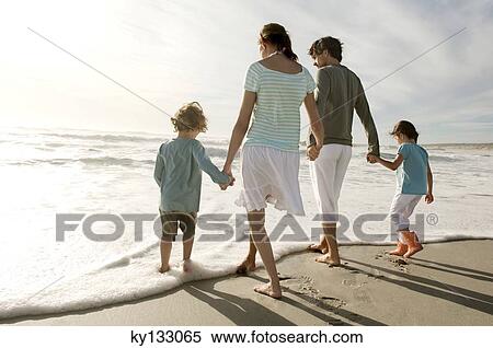 Parents and two children walking on the beach, rear view, outdoors View Large Photo Image Stock Photography - Parents and two children walking on the beach, rear view, outdoors. Fotosearch