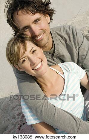 Portrait of a couple smiling on the beach, posing for the camera, outdoors View Large Photo Image Stock Photography - Portrait of a couple smiling on the beach, posing for the camera, outdoors. Fotosearch