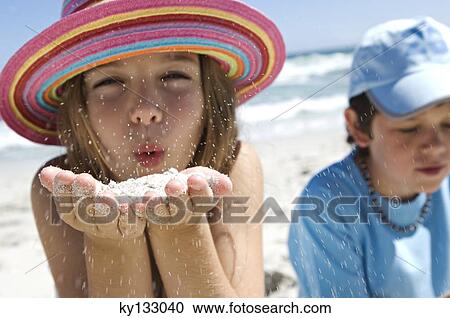 Portrait of a little girl blowing sand in her hands, boy in background, outdoors View Large Photo Image Stock Image - Portrait of a little girl blowing sand in her hands, boy in background, outdoors. Fotosearch