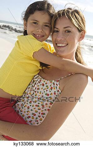 Portrait of a mother carrying her daughter, smiling, posing for the camera, outdoors View Large Photo Image Stock Photo - Portrait of a mother carrying her daughter, smiling, posing for the camera, outdoors. Fotosearch