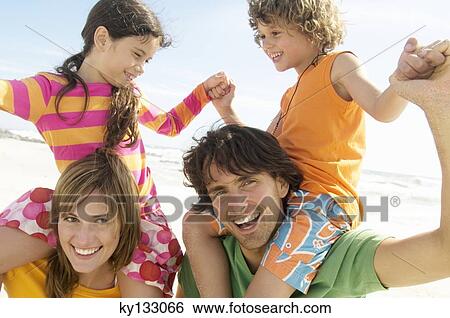 Portrait of parents carrying their two children on their shoulders, beach, outdoors View Large Photo Image Stock Photograph - Portrait of parents carrying their two children on their shoulders, beach, outdoors. Fotosearch