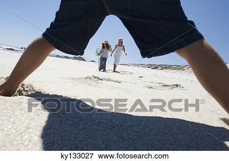 Stock Photo - Three children playing on the beach, outdoors. Fotosearch