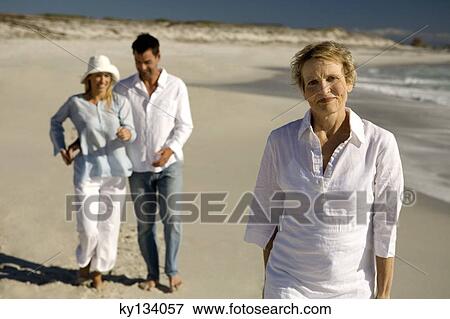 Couple embracing and senior woman waking on the beach View Large Photo Image Stock Photo - Couple embracing and senior woman waking on the beach. Fotosearch