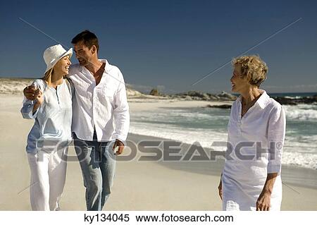 Couple embracing and senior woman waking on the beach View Large Photo Image Stock Photography - Couple embracing and senior woman waking on the beach. Fotosearch